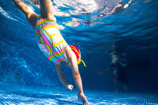 Little child swims underwater in swimming pool, happy active dives and has fun under water, kid fitness and sport 