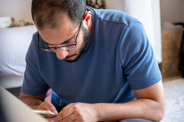 young bearded man making call while holding receipts