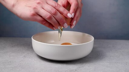 Female hands holding a cracked egg and breaking it. Cooking breakfast or baking. Protein food