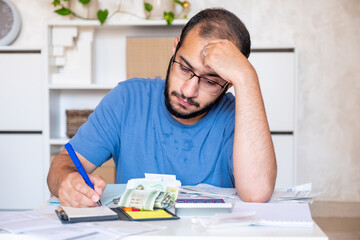 young bearded male callculating living costs in living room