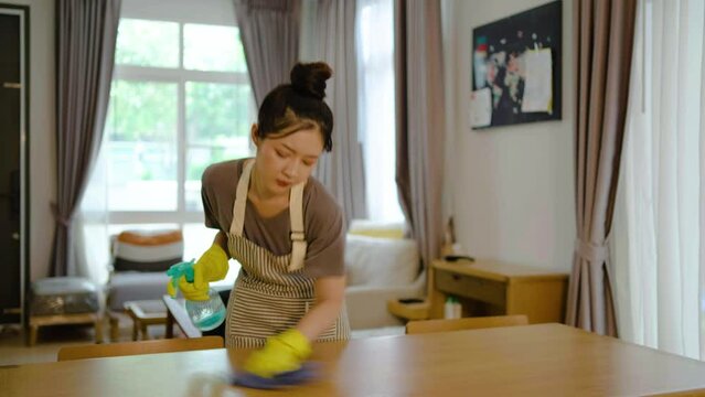 Asian beautiful cleaning service woman worker cleaning desk at home. Beautiful girl housewife housekeeper cleaner feel tired and upset while wiping dining table for housekeeping housework or chores