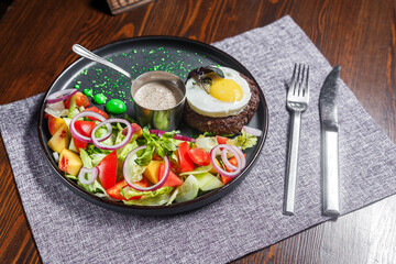 salad nicoise with vegetables and egg, on a plate, tablecloth on the table, dark and moody, top new