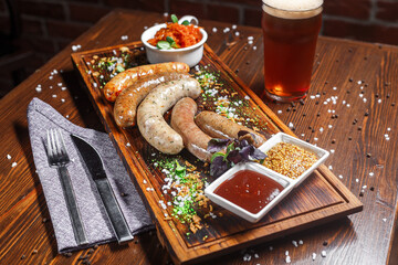 Small German boiled sausages, Nuremberg fried, on a plate, sauces and beer, dark and moody, top new