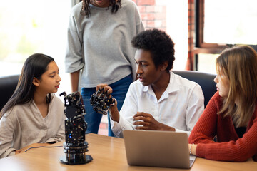 Happy diverse teens students group building robotic  hand using tablet computer. Building And...