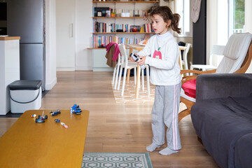 A 5-year-old girl plays a video game console at home.