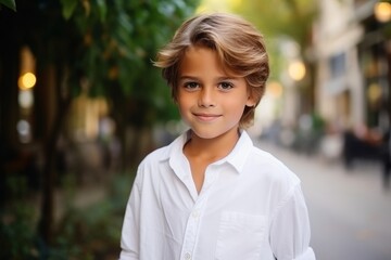 Portrait of a cute little boy with blond hair in a white shirt