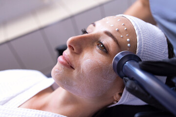 Closeup of face of beautiful relaxing girl undergoing hardware cosmetology procedure in spa