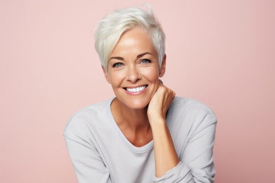 Smiling mature woman. Portrait of beautiful mature woman smiling while standing against pink background