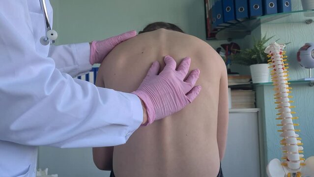 Chiropractor examining child with back pain in clinic. Spinal problem scoliosis and stoop in children