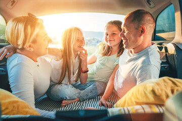  Portrait of happy smiling little sisters. Happy young couple with two daughters inside the car...