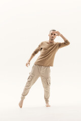 A young man in a beige jumper and cargo pants on a white background