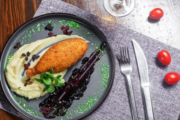 Chicken Kiev cutlet with mashed potatoes, on a plate, croutons and a glass of wine, dark and moody, top new