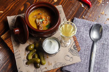 baked meat with vegetables in a clay pot, gherkins and white sauce dark and moody, top new