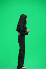 A woman in black clothes, on a green background, in full height