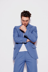 Fashionable brunette man in eyeglasses and blue suit looking at camera on grey