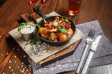 Fried potatoes with mushrooms and chicken in a cast iron frying pan, dark and moody, top new