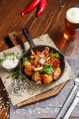 Fried potatoes with mushrooms and chicken in a cast iron frying pan, dark and moody, top new