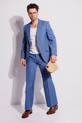 Stylish man in blue vintage suit holding paper bag on grey with shadow