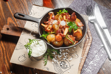 Fried potatoes with mushrooms and chicken in a cast iron frying pan, dark and moody, top new