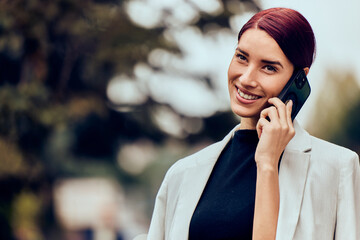 A portrait of a beautiful red-haired woman, talking to someone over the phone.