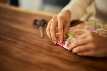 Female hands are wrapping a gift into the decoration paper.