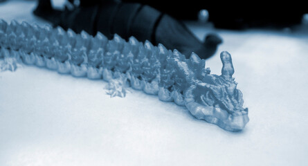 Prototype of blue dragon 3D printed from melted plastic. Close-up model of toy created on 3D...
