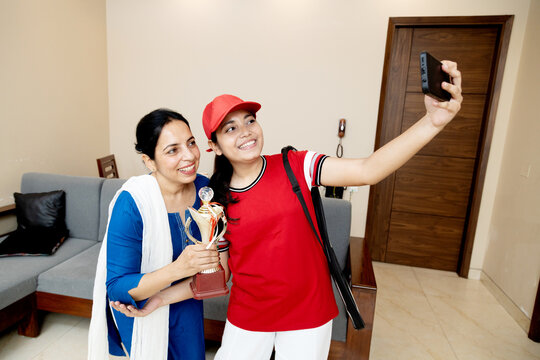 Overjoyed Indian mother daughter taking selfie with winning trophy