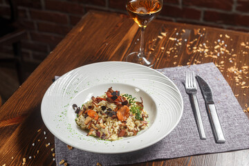 Risotto dish on a white plate and a glass of wine, dark and moody, top new