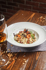 Risotto dish on a white plate and a glass of wine, dark and moody, top new