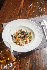 Risotto dish on a white plate and a glass of wine, dark and moody, top new