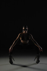 Young woman in black bodice and tights poses on black backlit studio background. Female dancer...