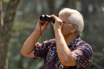 Adventurous senior man using binoculars