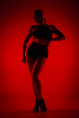 Silhouette female dancer in black shorts and top. Young woman poses gracefully and shows off...