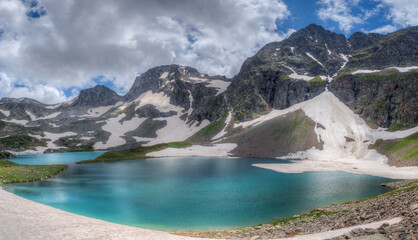Turquoise lake among snow-capped mountains.