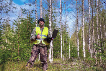 ecologist works in a young forest with a computer.
