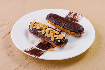Chocolate eclairs with almonds on plate