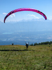 Gleitschirmstart in den K&auml;rntner Alpen bei strahlendem Sonnenschein

