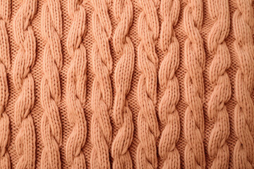 A close up of a peach fuzz  knitted sweater with a large braid suitable for winter fashion websites, knitting blogs, cozy apparel advertisements, and seasonal social media posts. - obrazy, fototapety, plakaty