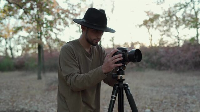 Arabic stylish man taking photo of landscape and nature with modern camera on tripod
