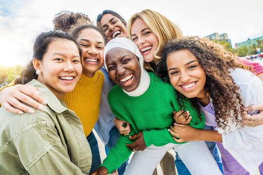 Multi ethnic group of young women hugging outside - Happy girlsfriends having fun laughing out loud on city street - Female community concept with cheerful girls standing together - Women  power