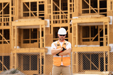 roofer builder working on roog structure of building on construction site. handsome young male builder in hard hat smiling at camera. Construction Worker on Duty. Contractor and the Wooden House Frame