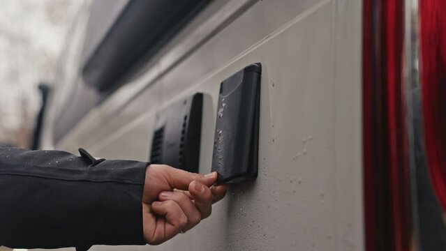 Close-up of a hand opening a water tank on a camper van