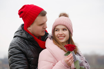 A man gives a red rose to a young woman