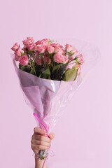 A child's hand holds a bouquet of pink roses