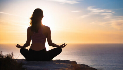 Young woman practicing yoga at sunset on a cliff overlooking the ocean. - Powered by Adobe