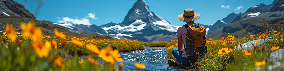 Handsome young man with a backpack sitting on a meadow in front of Matterhorn