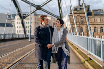 Handsome man and beautiful woman hugging each other as they walk around city, having a fun time, lifestyle photo