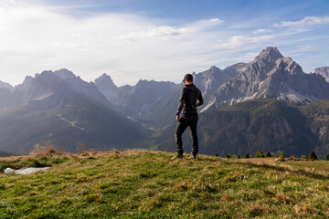 Naklejka na ściany i meble Hiker man with scenic view of majestic mountain peaks of untamed Sexten Dolomites in South Tyrol, Italy, Europe. Hiking on Monte Elmo in autumn. Wanderlust concept in Italian Alps. Tranquil atmosphere