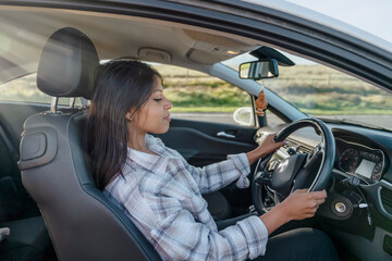 Naklejka premium Portrait of a young woman sitting in a car and holding on to the steering wheel. Buy your first car concept