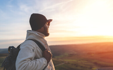 happy handsome man tourist with backpack hiking and enjoying mountains landscape at sunset in...